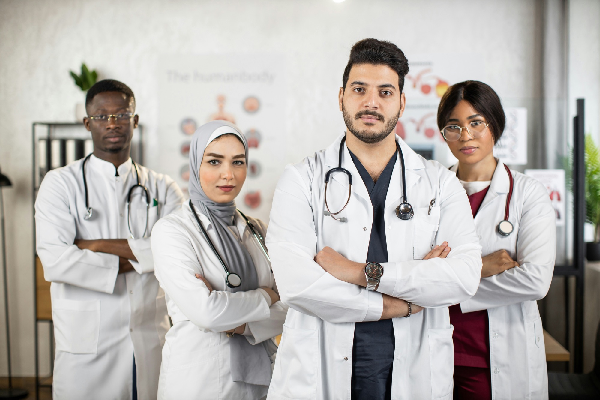 Four doctors standing with arms crossed, one man front and centre with colleagues behind him