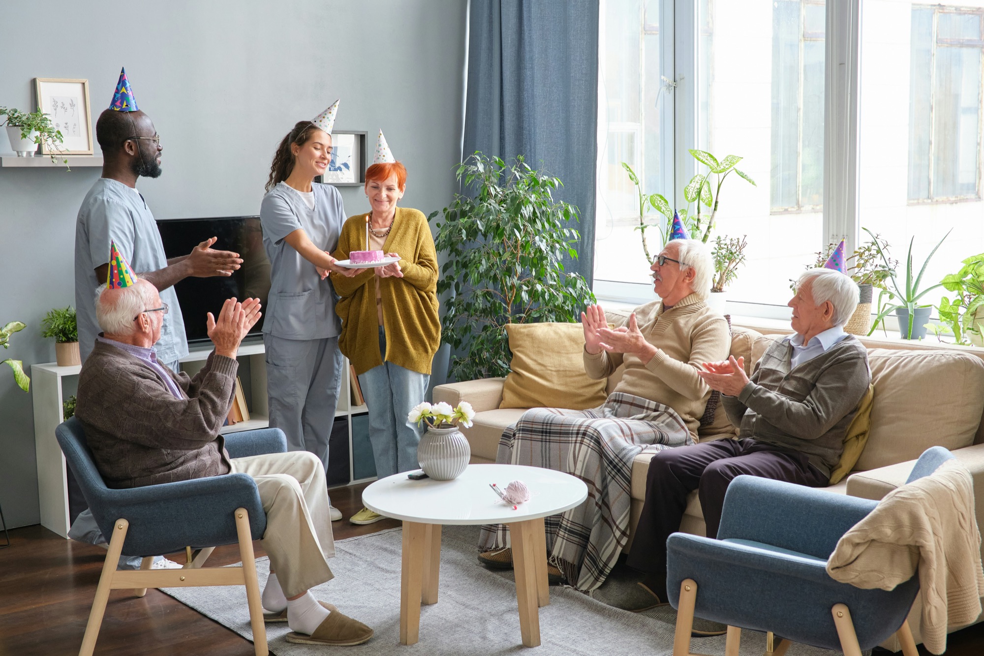 Care staff and residents celebrating together in a bright aged care lounge