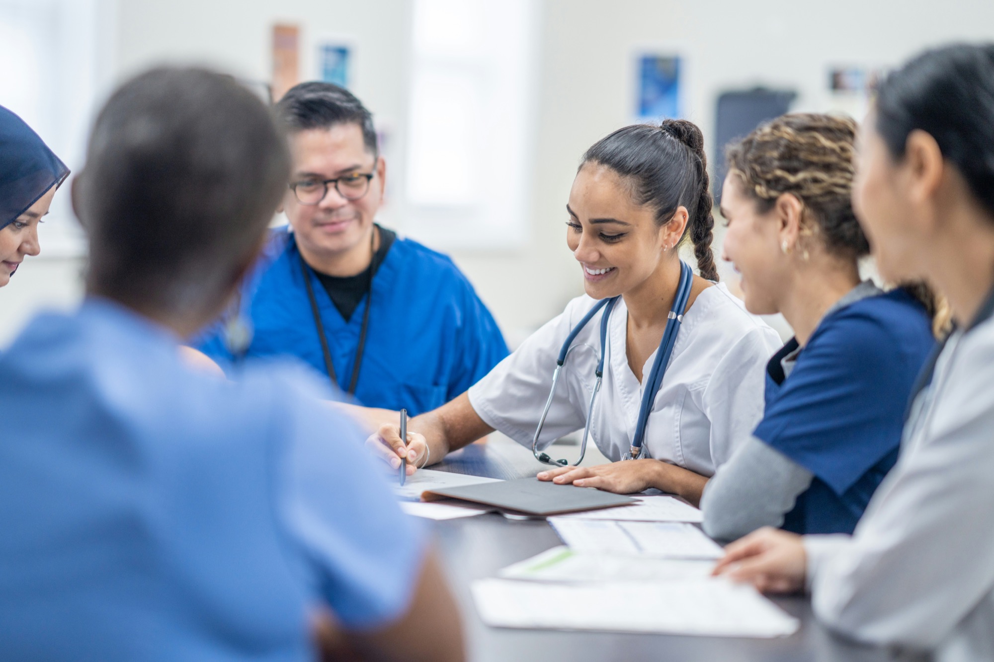 A diverse clinical team smiling and talking around a meeting table