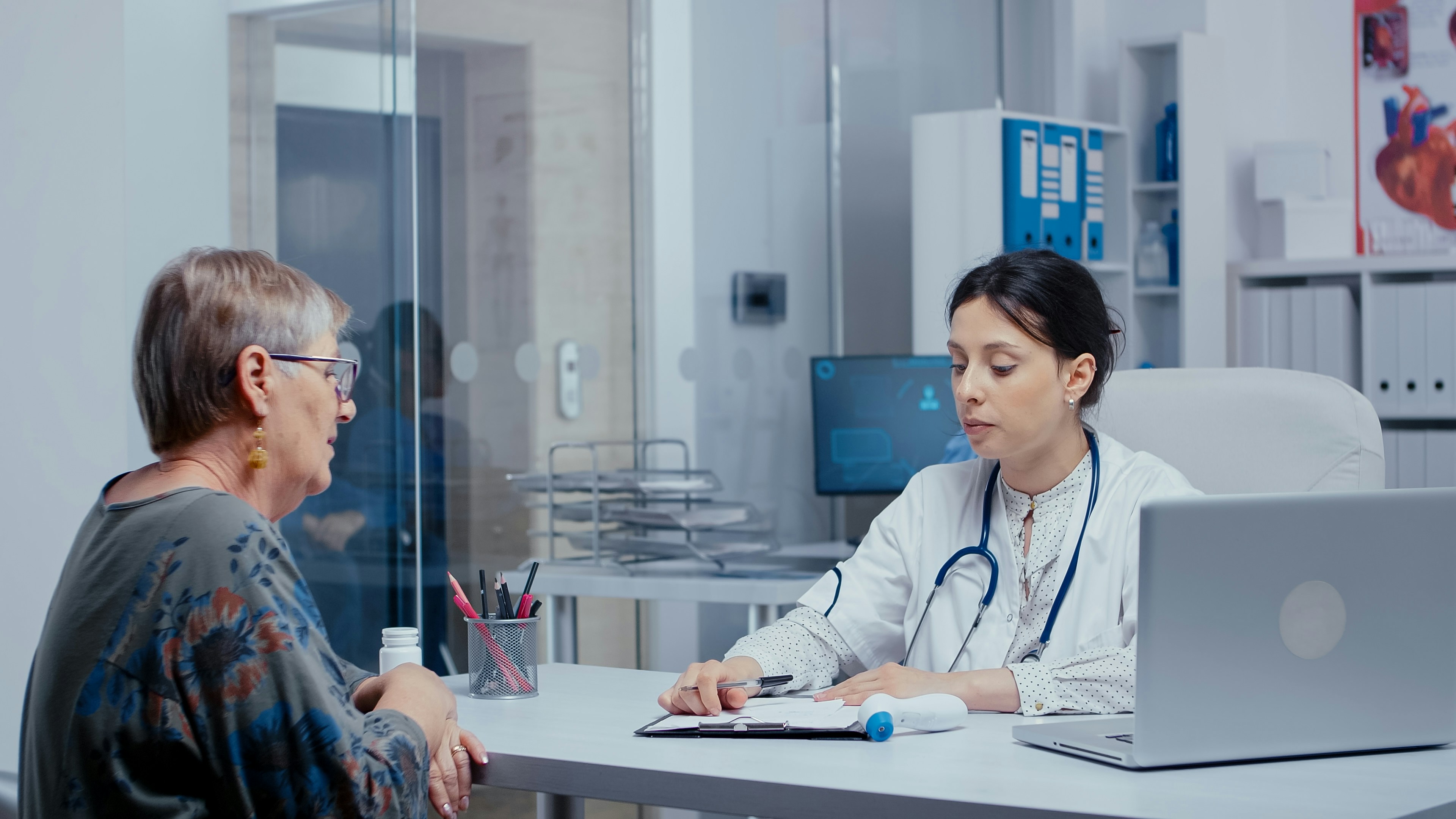 An older female patient in consultation with a younger female doctor at a clinic desk
