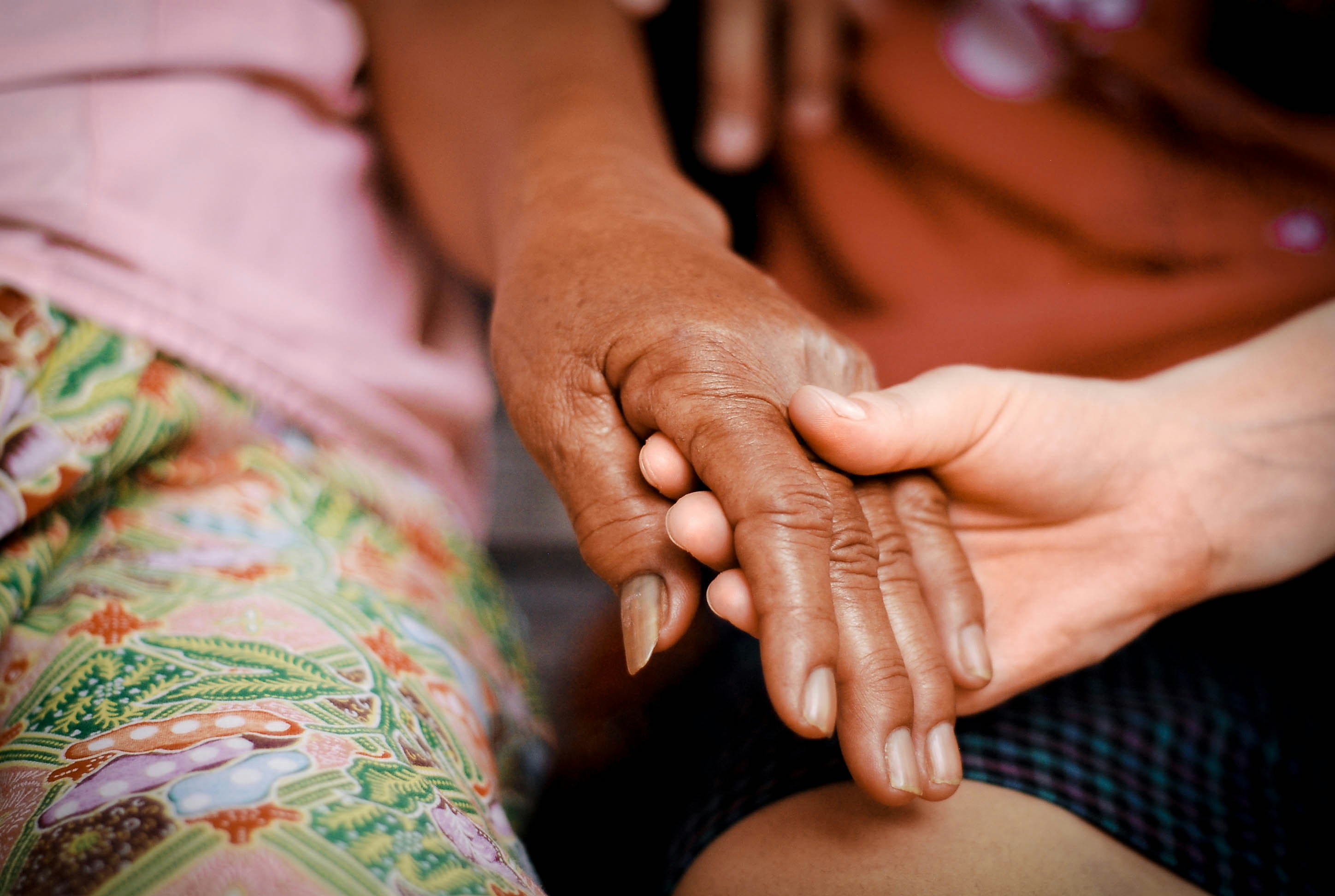 Two people holding hands in a gesture of care and connection